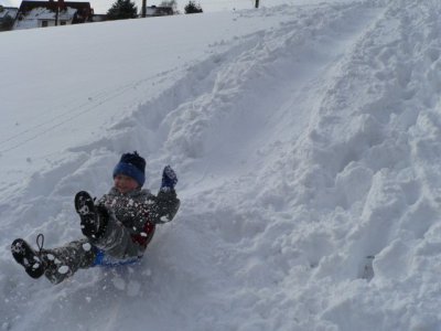 Kinder im Schnee rutschen Berg herunter